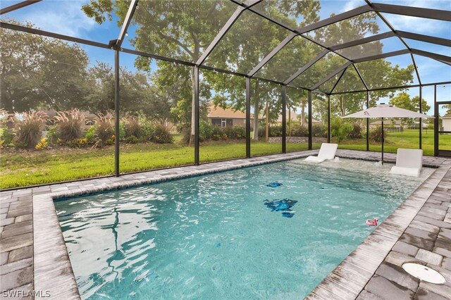 view of pool with a lanai, a patio area, and a lawn