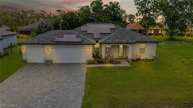 view of front of house featuring solar panels, a garage, and a lawn