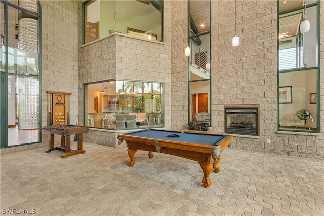 rec room featuring a high ceiling, billiards, and a tiled fireplace