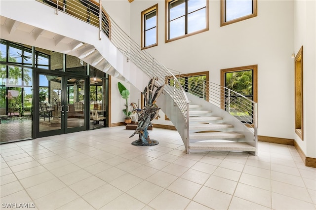 staircase featuring tile patterned flooring, a high ceiling, and french doors