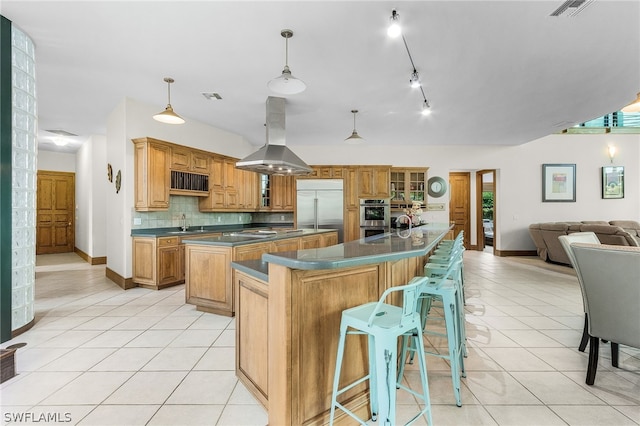 kitchen featuring island exhaust hood, backsplash, stainless steel appliances, a spacious island, and hanging light fixtures