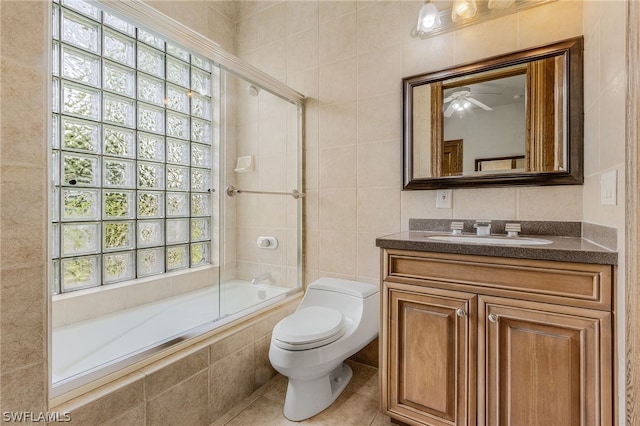 full bathroom featuring tile patterned flooring, enclosed tub / shower combo, toilet, vanity, and tile walls