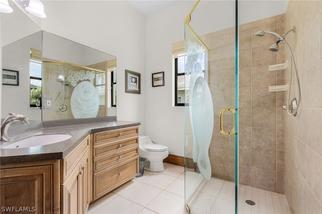 bathroom featuring toilet, vanity, tile patterned floors, and a shower with shower door