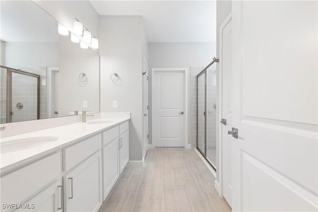 bathroom featuring a shower with door and vanity