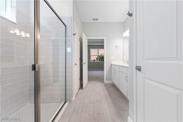 bathroom with a shower with door, vanity, and hardwood / wood-style floors