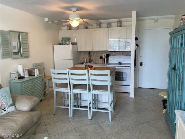 kitchen with white cabinetry, ceiling fan, backsplash, white appliances, and a breakfast bar