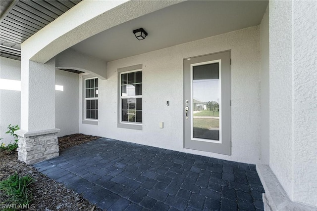 view of exterior entry featuring a patio area