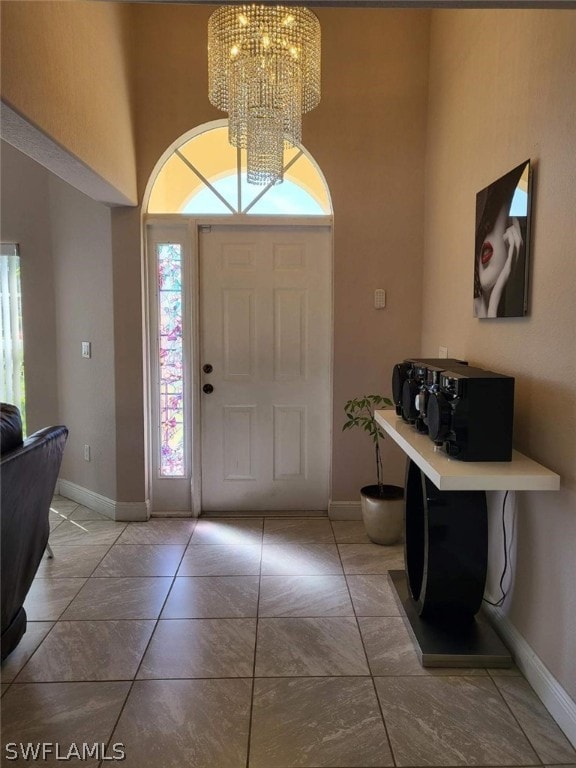 foyer entrance featuring a high ceiling, light tile patterned floors, and a chandelier