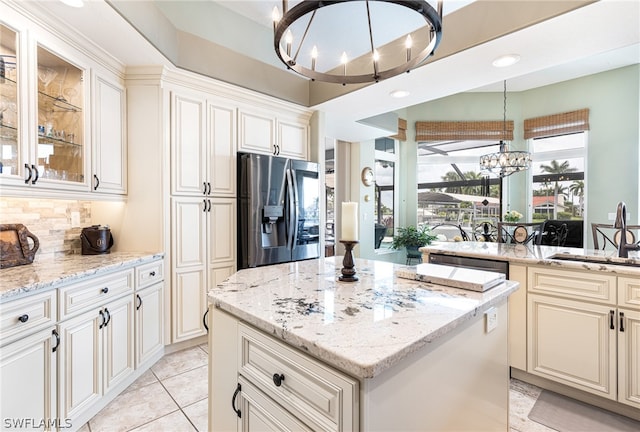 kitchen featuring appliances with stainless steel finishes, light stone countertops, sink, and a notable chandelier