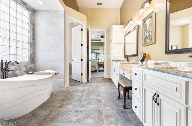 bathroom with tile walls, vanity, a bath, and ceiling fan