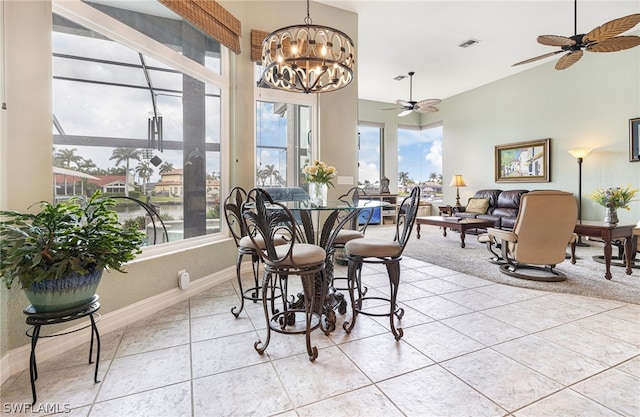 dining space featuring light tile patterned floors, ceiling fan with notable chandelier, and plenty of natural light