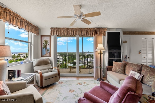 living area with a textured ceiling, wood finished floors, and a ceiling fan