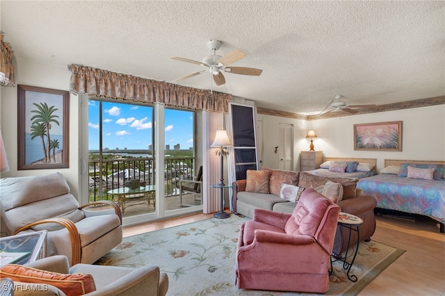 bedroom with ceiling fan, a textured ceiling, hardwood / wood-style floors, and access to exterior