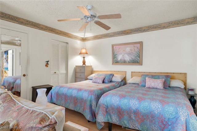 bedroom with ceiling fan, wood finished floors, a closet, and a textured ceiling