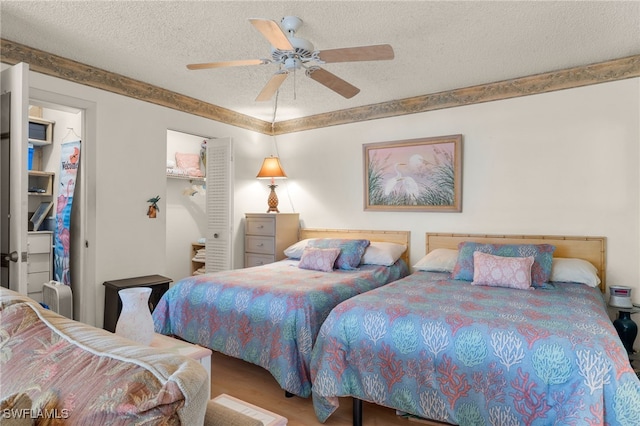 bedroom with ceiling fan, a textured ceiling, a closet, and hardwood / wood-style floors