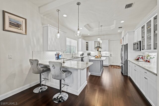 kitchen with pendant lighting, a breakfast bar, white cabinets, and stainless steel appliances