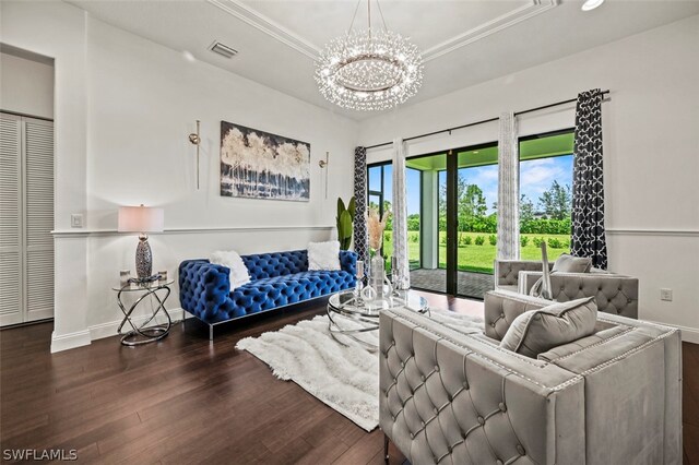 living room featuring a chandelier, hardwood / wood-style flooring, a raised ceiling, and crown molding