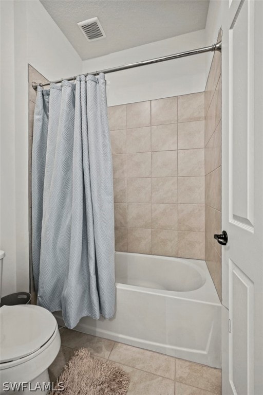 bathroom featuring tile patterned flooring, toilet, a textured ceiling, and shower / tub combo with curtain