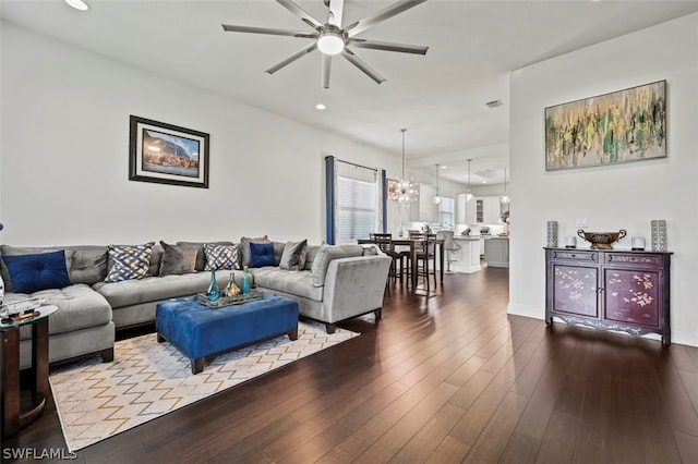 living room featuring ceiling fan with notable chandelier and light wood-type flooring