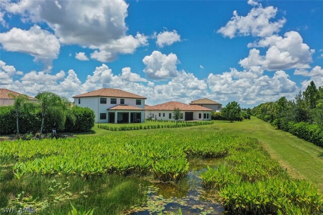 rear view of house with a yard and a water view