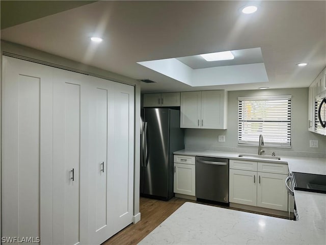 kitchen with dark wood-type flooring, sink, white cabinetry, a raised ceiling, and stainless steel appliances