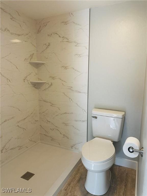 bathroom with hardwood / wood-style flooring, tiled shower, and toilet