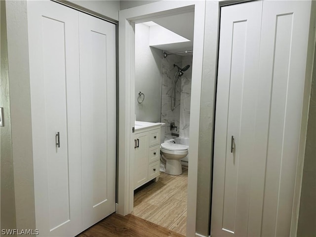 full bathroom featuring vanity, hardwood / wood-style floors, tiled shower / bath, and toilet