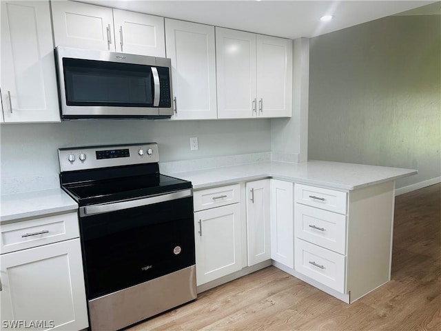 kitchen featuring stainless steel appliances, white cabinets, light hardwood / wood-style floors, and kitchen peninsula