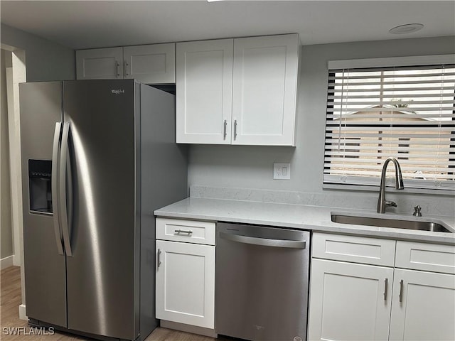 kitchen featuring sink, hardwood / wood-style flooring, stainless steel appliances, and white cabinets