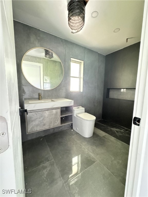 bathroom with tile walls, tile patterned floors, toilet, and vanity