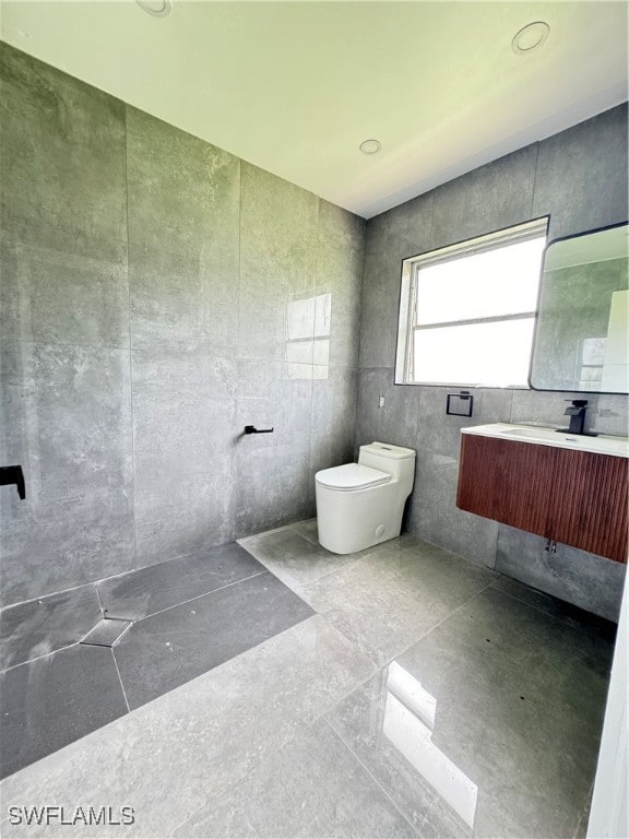 bathroom featuring vanity, toilet, tile patterned flooring, and tile walls