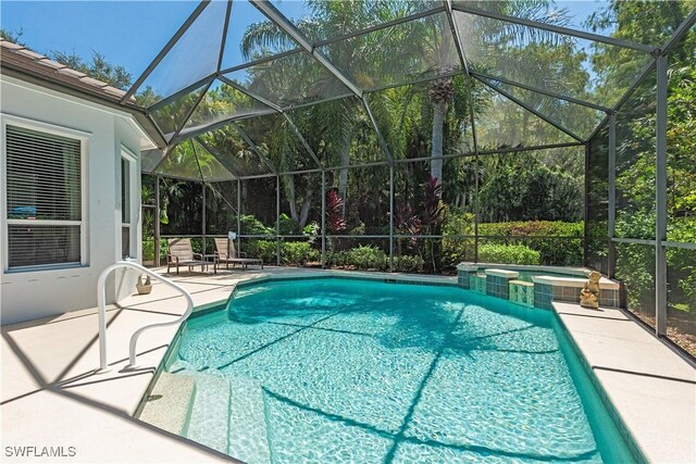 view of swimming pool featuring an in ground hot tub, a patio, and a lanai