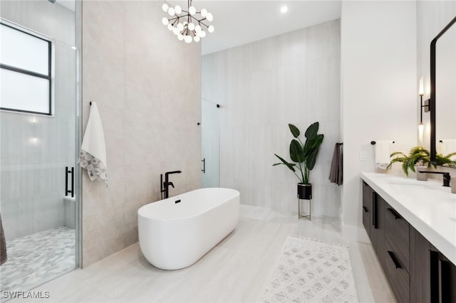 bathroom with vanity, shower with separate bathtub, a chandelier, and tile walls