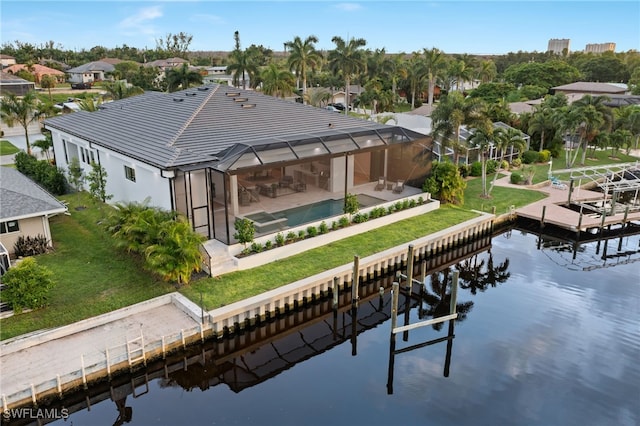 rear view of house with a water view, a yard, and glass enclosure