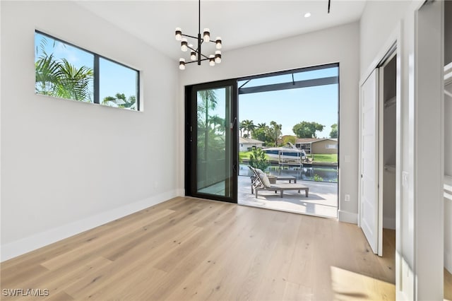 doorway to outside featuring light hardwood / wood-style flooring, a chandelier, and a water view