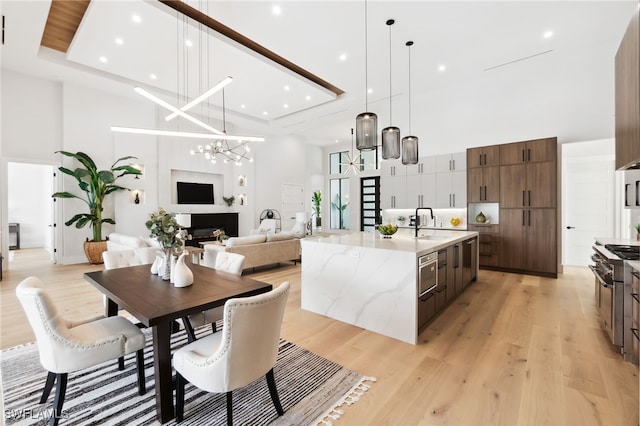 kitchen featuring high end stainless steel range, sink, light stone counters, pendant lighting, and a large island