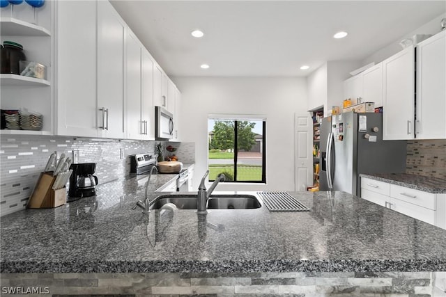 kitchen featuring stainless steel appliances, white cabinetry, sink, and dark stone countertops