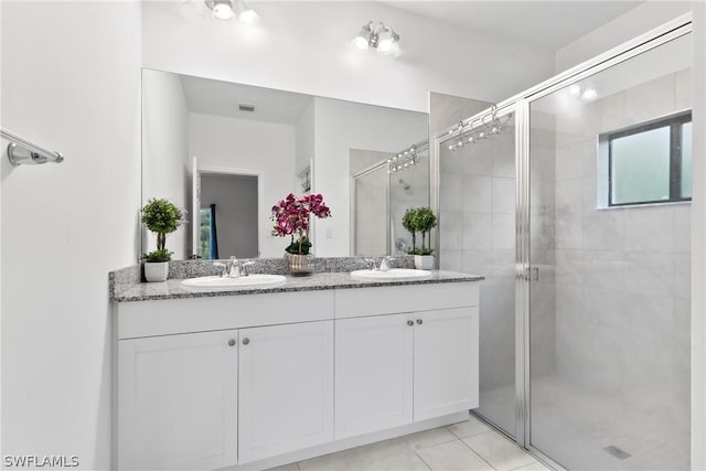 bathroom with tile patterned flooring, vanity, and walk in shower