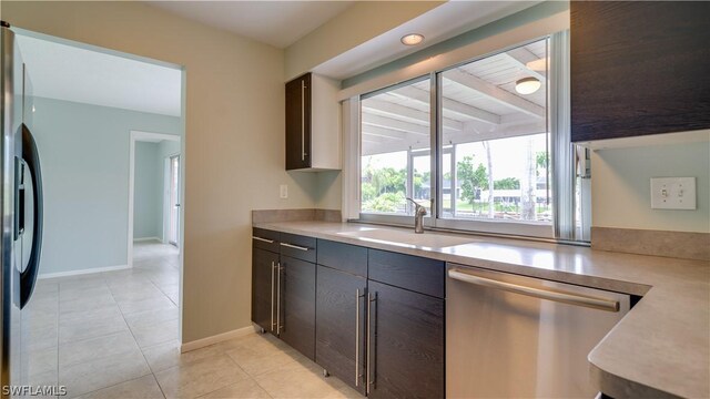 kitchen featuring sink, light tile patterned floors, dark brown cabinets, and appliances with stainless steel finishes