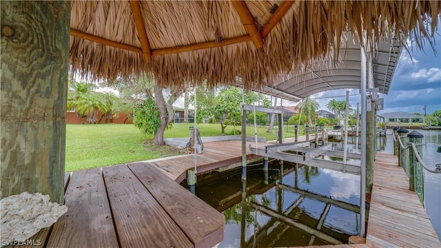 view of dock with a water view and a lawn