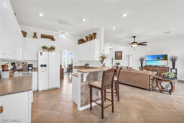 kitchen featuring white cabinetry, white appliances, a kitchen breakfast bar, ceiling fan, and light tile patterned floors