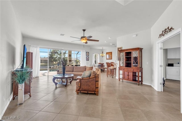 living room with ceiling fan with notable chandelier, washer / dryer, and light tile patterned flooring