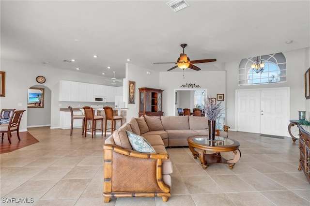 tiled living room with ceiling fan with notable chandelier