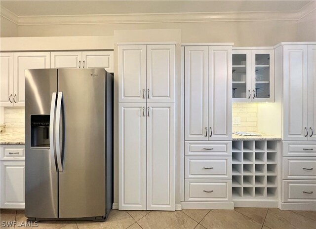 kitchen featuring stainless steel fridge with ice dispenser, light stone countertops, decorative backsplash, and light tile patterned floors