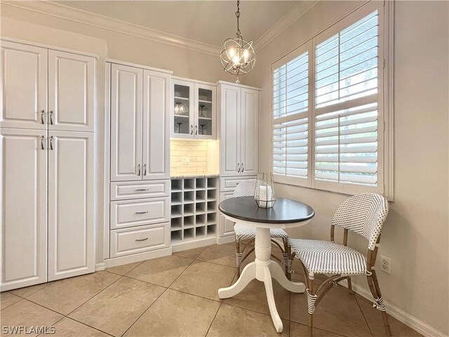 tiled dining area featuring a notable chandelier and ornamental molding