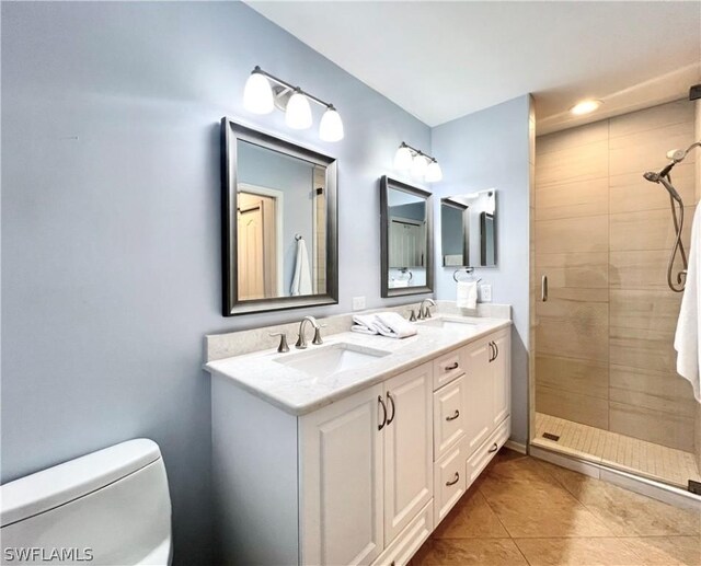 bathroom with dual vanity, tiled shower, tile patterned floors, and toilet