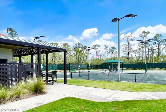 view of property's community featuring a tennis court and fence