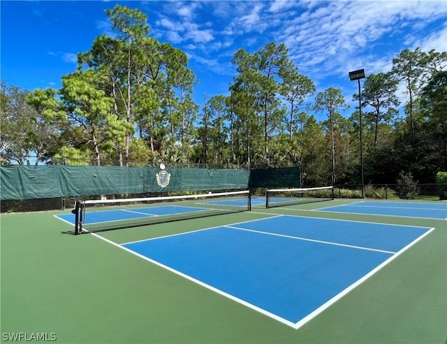 view of tennis court with community basketball court and fence