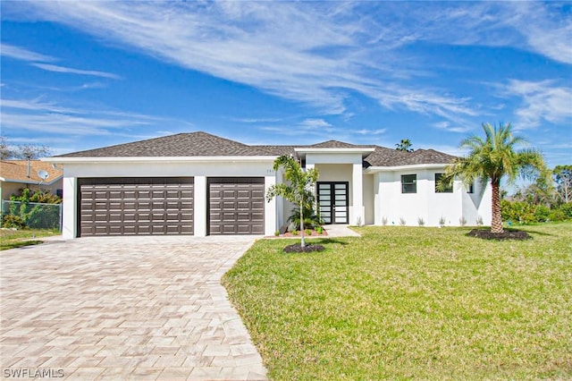 prairie-style house with a garage, a front lawn, decorative driveway, and stucco siding