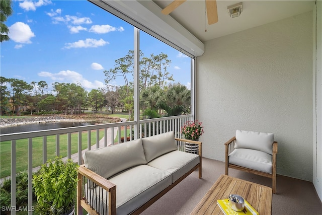 sunroom / solarium with ceiling fan and a water view